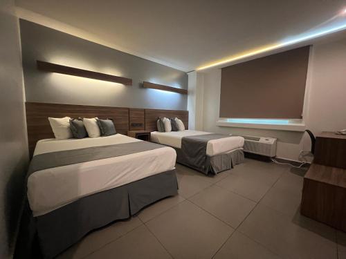 ein Hotelzimmer mit zwei Betten und einem großen Fenster in der Unterkunft Hotel El Sembrador in Guasave