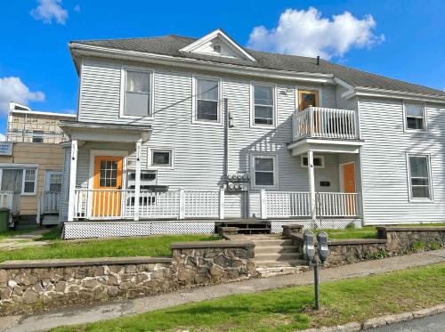 a white house with orange doors on a street at King Bed 2BR near the LaHave River and Trails in Bridgewater
