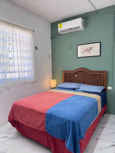 a bedroom with a bed with a red and blue blanket at Casa verde El Platanar con Jardín Tropical Calkiní in Calkiní