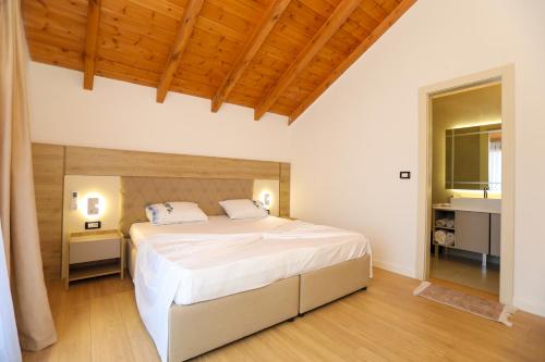 a bedroom with a large white bed with a wooden ceiling at Guesthouse Micaj ERDEO in Hor