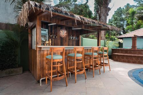 a bar with wooden stools in front of a bar at Verano Hotel & Spa Arpora Goa in Arpora