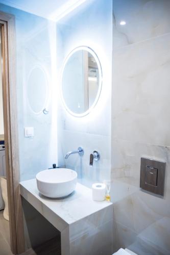 a white bathroom with a sink and a mirror at Akrolithos apartments 1st floor in Platy