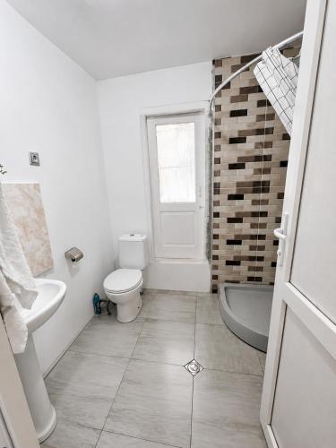 a white bathroom with a toilet and a sink at Utsera Veranda in Utsera