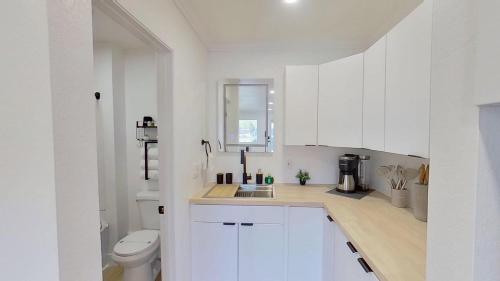 a white kitchen with a sink and a toilet at Hygge Hus Hotel in Andrews