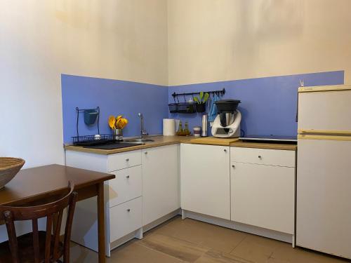 a kitchen with white cabinets and a blue wall at Domu hermosa in Villaputzu
