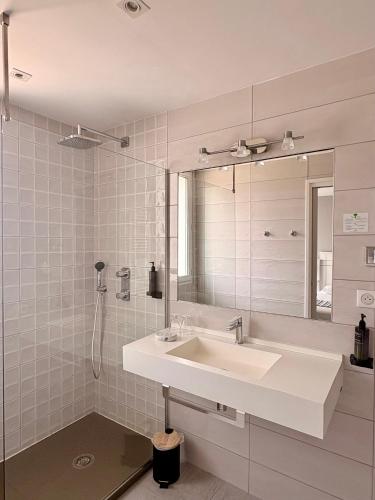 a white bathroom with a sink and a mirror at Hôtel Valencia in Hendaye