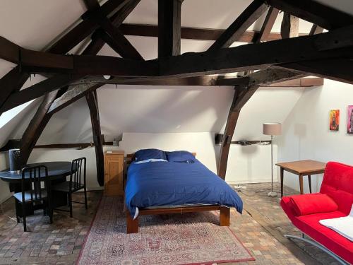 a bedroom with a bed and a red couch at La maison aux volets bleus in Laval