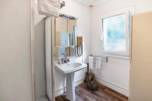 a white bathroom with a sink and a window at Hotel de la Bonnheure in Bracieux