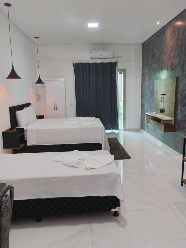 a bedroom with two beds and a bathroom at Suíte Lençóis - Quarto amplo com Cozinha Integrada in Lençóis