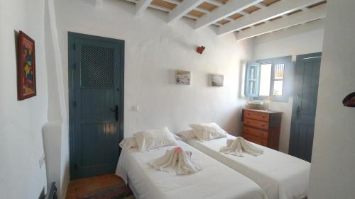 a bedroom with a bed with white sheets and a blue door at Casa Dulce in Vejer de la Frontera
