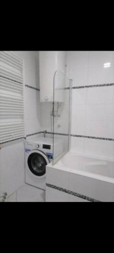 a white bathroom with a washing machine and a window at Panorama View in Niš