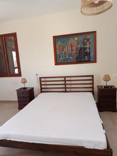 a bedroom with a bed with two nightstands and a painting at Casa de los Encantos in Vila do Porto