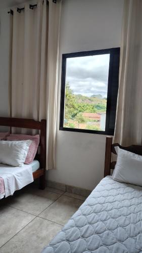 a bedroom with two beds and a window at Pousada dos Cuiabás in Tiradentes