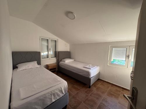a bedroom with two beds and two windows at Apartmani Srdanovic in Tivat