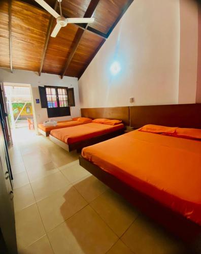 two beds in a room with orange sheets at Hotel PalmaSol in Ricaurte
