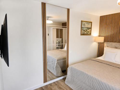 a bedroom with a mirror next to a bed at Kopų gatvės studija Nidoje in Nida