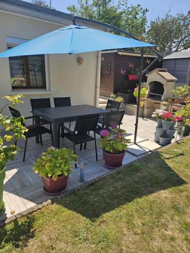 a black table and chairs under a blue umbrella at Maison confortable à Ver-sur-Mer avec jardin privé in Ver-sur-Mer