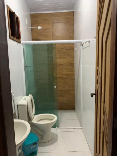a bathroom with a toilet and a glass shower at Beach House in Barra dos Coqueiros