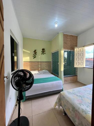 a bedroom with two beds and a fan at Beach House in Barra dos Coqueiros