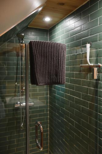 a green tiled bathroom with a shower and a towel at Triangle de l'île Chambre le Grenier in Saint-Laurent-de-l'ile d'Orleans