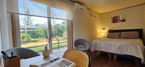 a bedroom with a bed and chairs and a window at Alojamiento Zapallar in Curicó