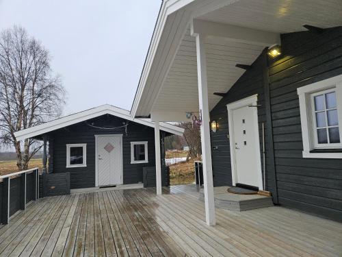 ein schwarzes Haus mit Veranda und weißer Tür in der Unterkunft T - Stua in Moen i Målselv