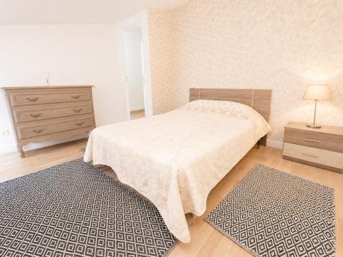 a bedroom with a bed and a dresser and two rugs at sejour climatisé avec chambres avec ventilateurs in Bourgoin