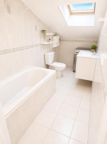a white bathroom with a tub and a toilet at sejour climatisé avec chambres avec ventilateurs in Bourgoin