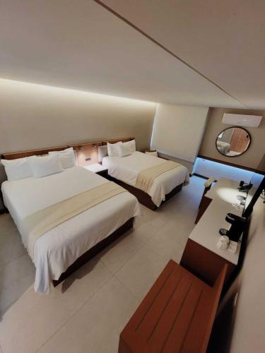 a hotel room with two beds and a table at Hotel Alameda in Tegucigalpa