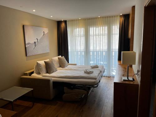 a bedroom with a bed and a large window at Alpine Apartment Andermatt in Andermatt