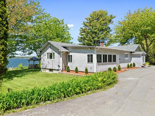 a white house with a driveway at Charming home with stunning bay views, sunroom, gazebo, deck, & grill in Trenton
