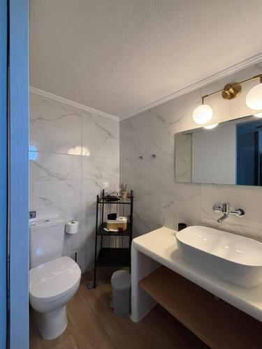 a white bathroom with a toilet and a sink at Enalia Apartments in Korissia