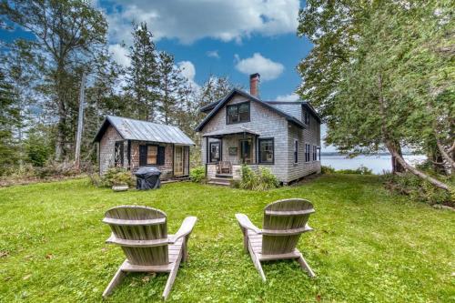 two chairs sitting in front of a house at Waterfront dog-friendly cottage with amazing views, deck, grill, & washer/dryer in Cushing