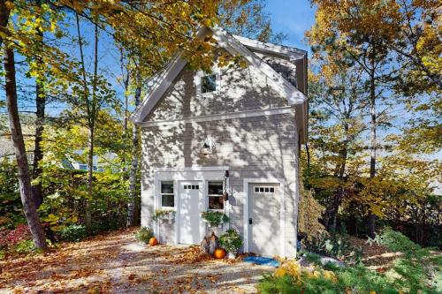 a small white house in the middle of the woods at Charming coastal cottage with firepit and easy beach access in Rockport