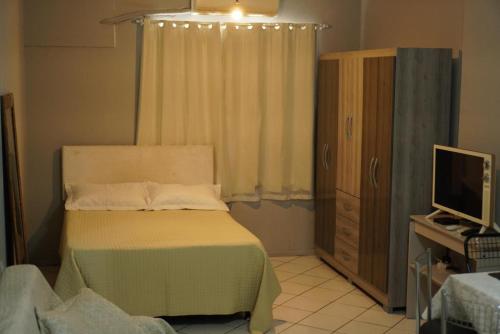 a bedroom with a bed and a dresser and a television at Studio Centro Floripa 02 in Florianópolis
