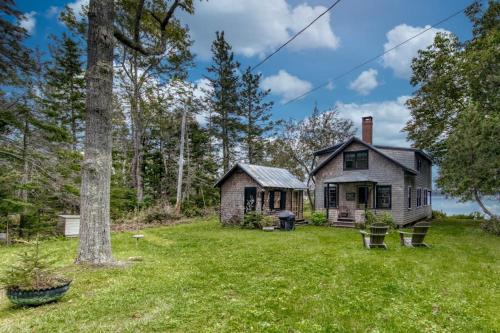 an old house in the middle of a yard at Waterfront dog-friendly cottage with amazing views, deck, grill, & washer/dryer in Cushing