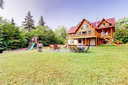a large wooden house with a playground and a slide at Tranquil Haven | Secluded waterfront house with sauna, dock, kayaks, canoe, gym in Greenville