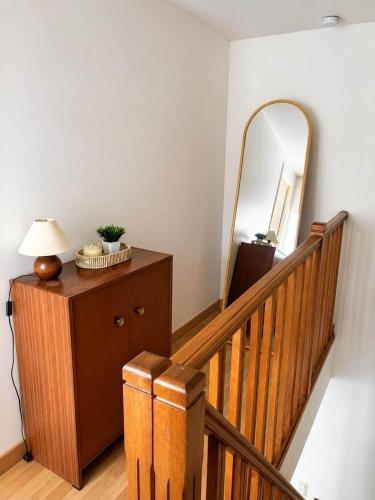 a staircase with a mirror and a wooden dresser with a lamp at L'Escale de Bonny in Bonny-sur-Loire