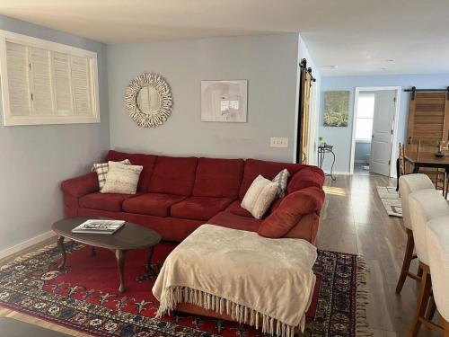 a living room with a red couch and a table at Pura Vida | A Calm Apt Escape Minutes from Camden in Camden