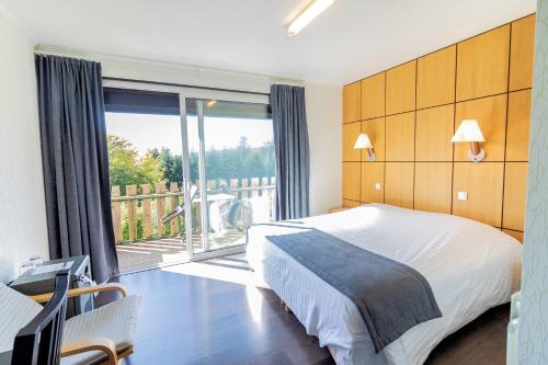 a bedroom with a bed and a balcony at Logis Clair Matin Resort & Spa in Le Chambon-sur-Lignon