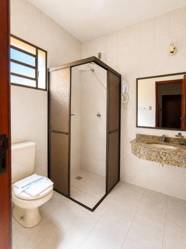 a bathroom with a shower and a toilet and a sink at Hotel São Lucas in Alfenas