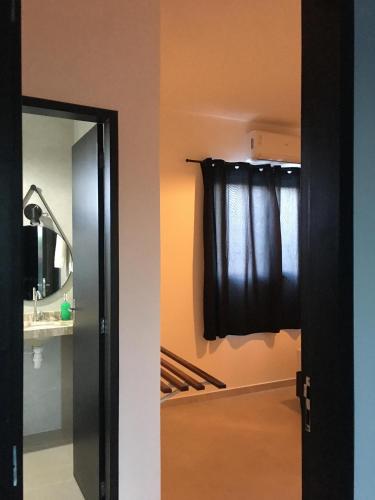 a bathroom with a mirror and a window with a curtain at Pousada Recanto dos Passaros in Aracati