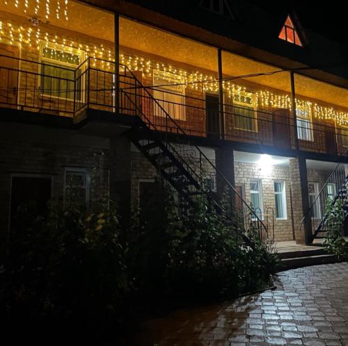 a building with lights on the side of it at night at Гостевой дом Арай in Bosteri