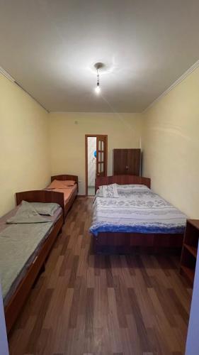 two beds in a room with wooden floors at Гостевой дом Арай in Bosteri