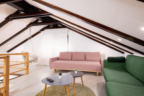 a living room with a pink couch and green chairs at Timber Fairies in Slunj