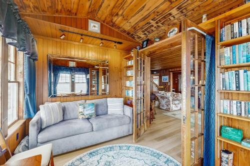 a living room with a couch and some books at Dog-friendly, bayfront home - gorgeous ocean views, private balcony & fireplace in East Boothbay