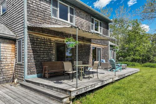 a deck with a table and chairs on a house at Waterfront stay with scenic deck, grill, smart TVs, shore access - dog-friendly in Penobscot