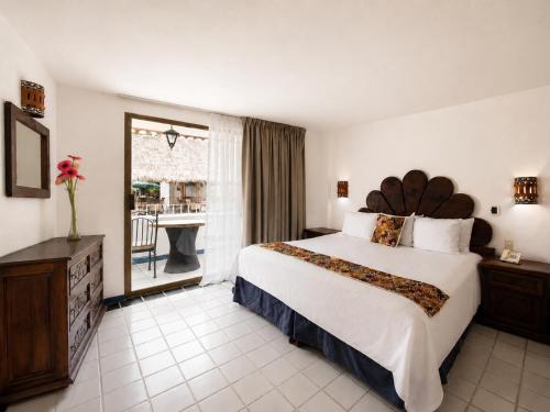 a hotel room with a large bed and a window at Los Arcos Suites in Puerto Vallarta