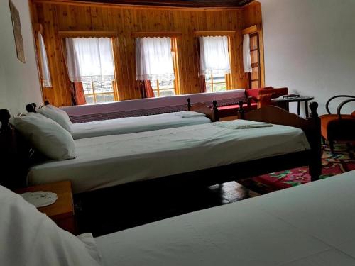a group of four beds in a room with windows at AmedaPm in Gjirokastër