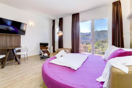 a bedroom with a large purple bed with a large window at Park Hotel Val Di Monte ***S in Malcesine